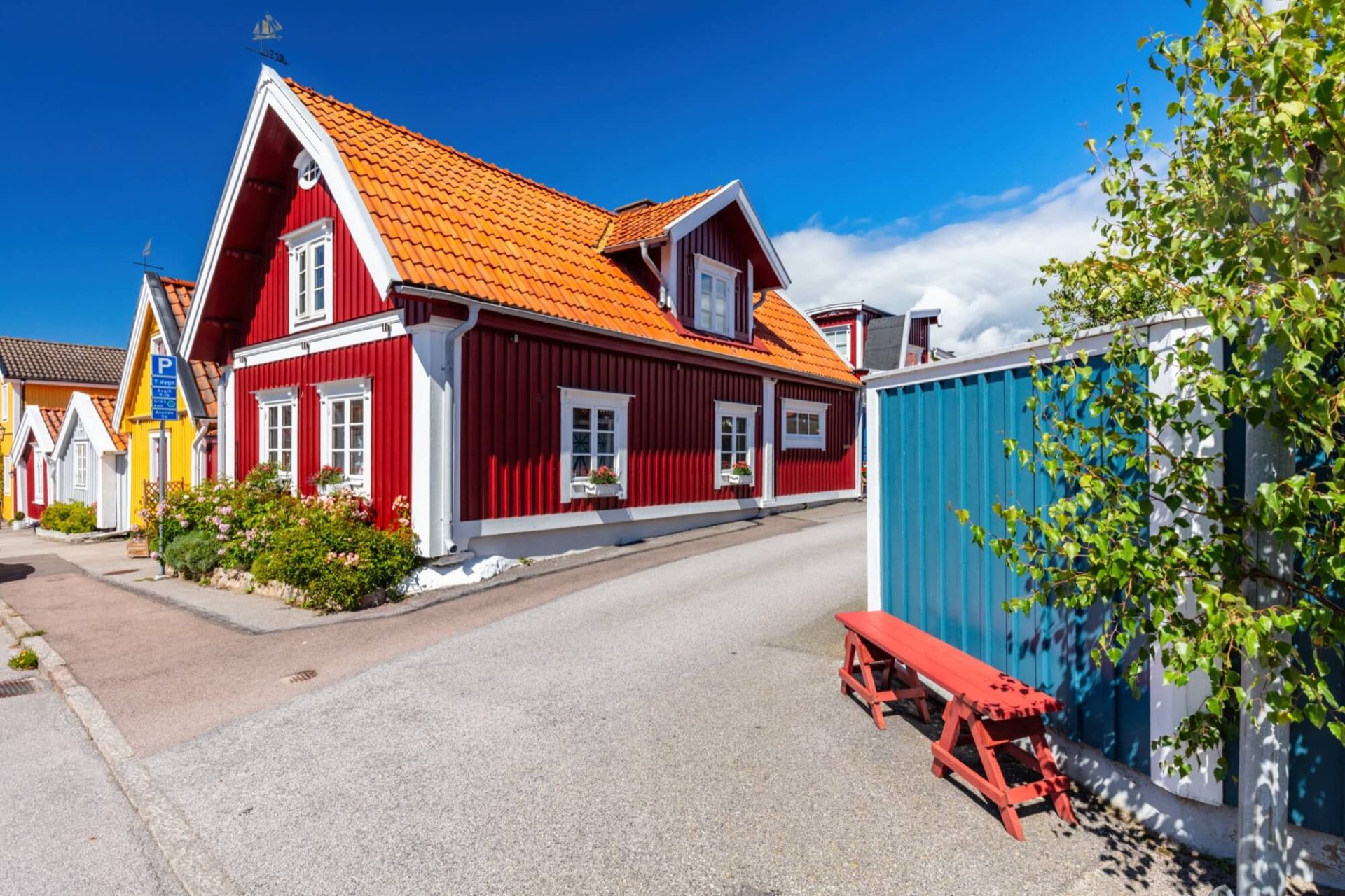 En klassisk skärgårdsidyll framhävs av ett rött trähus med vita knutar och ett orange tegeltak